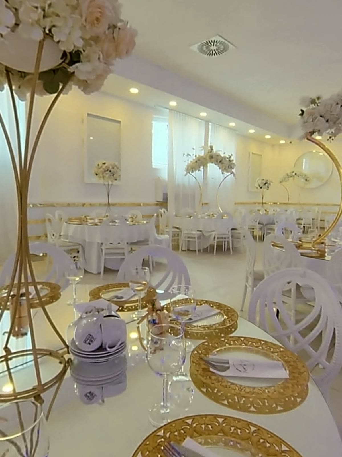 Runder Tisch mit goldenen Platztellern und Blumenschmuck
