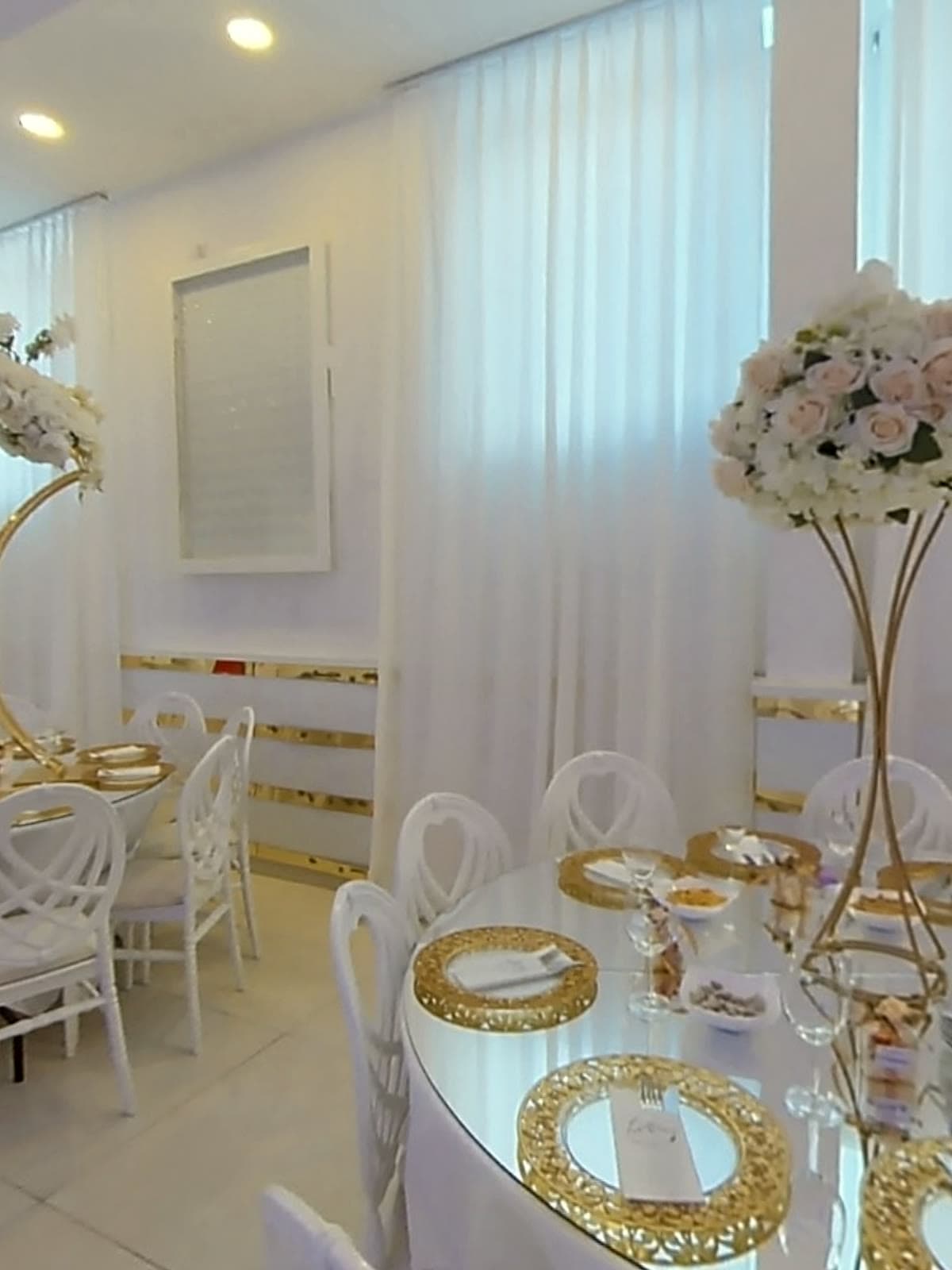 Lange Tafel mit goldenen Platztellern und Blumenschmuck
