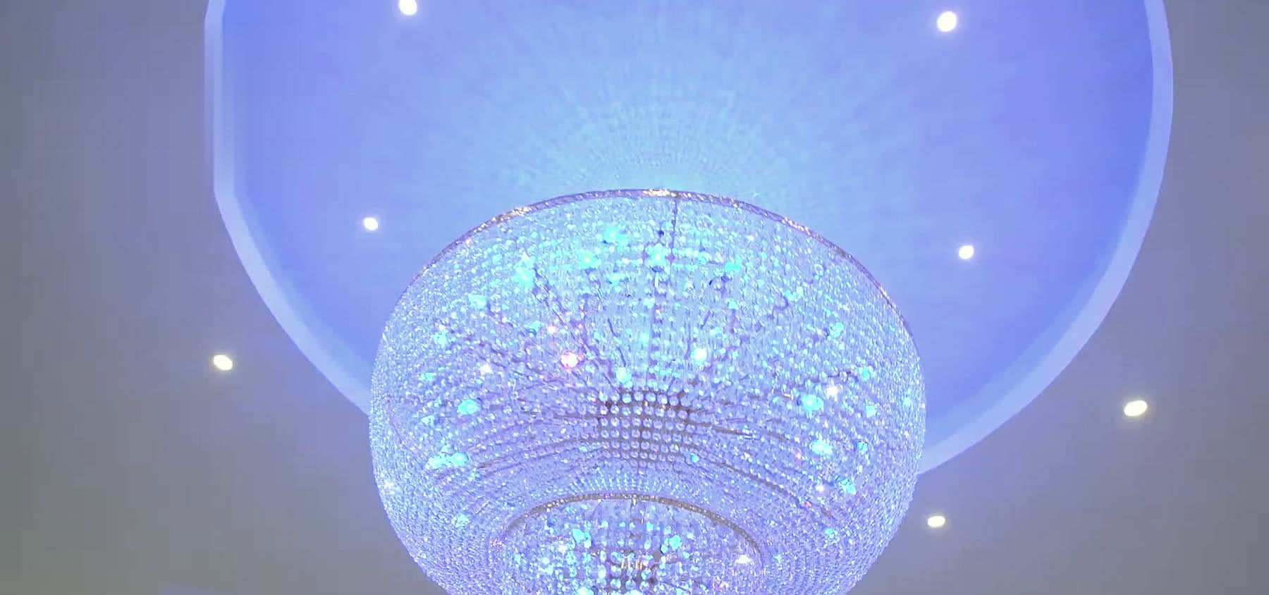 Kristallkronleuchter in blauem Licht unter der LED-Decke